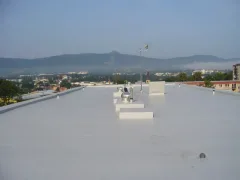 Plochá střecha s drobnými prostupy a panoramatem města a hor
