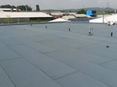 Střecha nízké průmyslové haly, kolem plechové budovy, slunečno