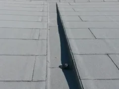 Detail shora na kout střechy se svarem, tmavý zrnitý povrch asfaltového pásu, malá hlavice