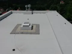 Bílý ventilační box na střeše orámovaný pruhem kačírku