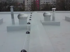 Dvě rotační ventilační hlavice na ploché střeše s bezpečnostním lanem