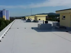 Zvýšený pohled podél zábradlí ploché střechy na malé město pod modrou oblohou