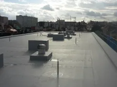 Roh ploché střechy s rotační hlavicí, zamlžené panorama města