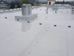 Plochá střecha s velkým boxem a tenkým stožárem, hory v pozadí, zataženo