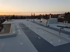 Soumrak nad rozpracovanou střechou, položená fólie a odkryté bednění na nástavbě, panorama města