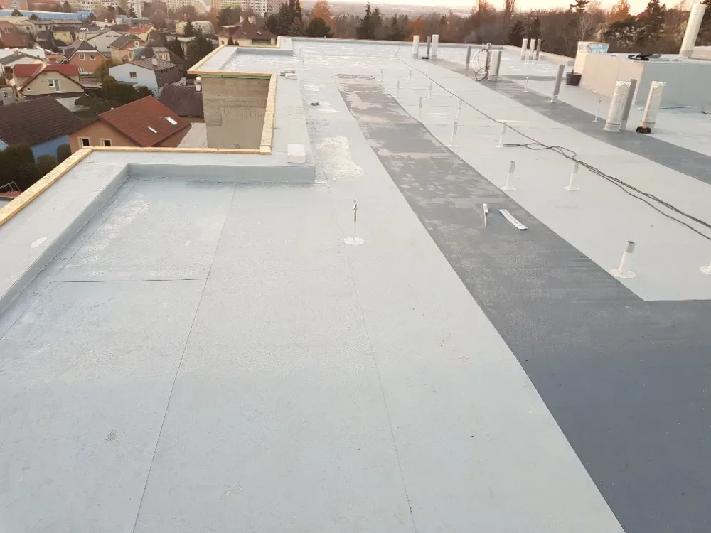 Rozpracovaná střecha za svítání s odkrytou tepelněizolační deskou a OSB lemem na atice
